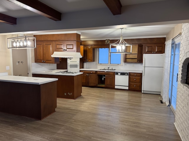 kitchen featuring sink, hanging light fixtures, a kitchen island, white appliances, and beam ceiling