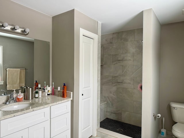 bathroom featuring vanity, tiled shower, and toilet