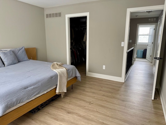 bedroom with a spacious closet, a closet, and light wood-type flooring