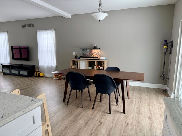 dining room featuring beam ceiling, light hardwood / wood-style flooring, and plenty of natural light