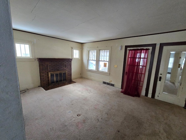 unfurnished living room with ornamental molding, a fireplace, and carpet floors