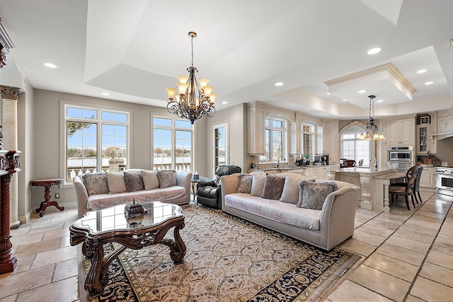 living room featuring an inviting chandelier, plenty of natural light, and a raised ceiling