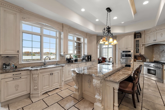 kitchen with a center island with sink, glass insert cabinets, light stone counters, a water view, and a sink