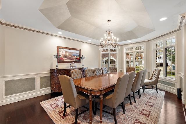 dining space featuring a wainscoted wall, dark wood-type flooring, a tray ceiling, crown molding, and a decorative wall