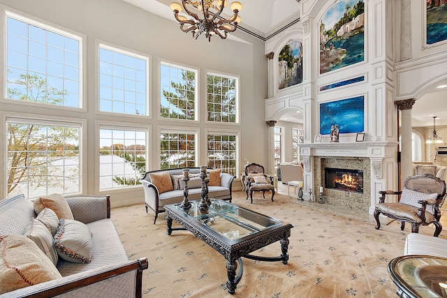 living room featuring a towering ceiling, a high end fireplace, and a chandelier