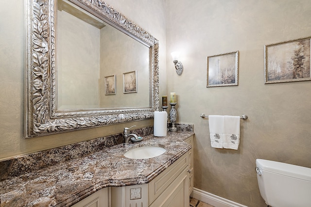 bathroom featuring toilet, vanity, and baseboards