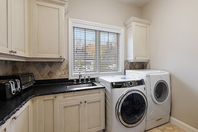 laundry room with cabinet space, baseboards, washing machine and dryer, a sink, and light tile patterned flooring