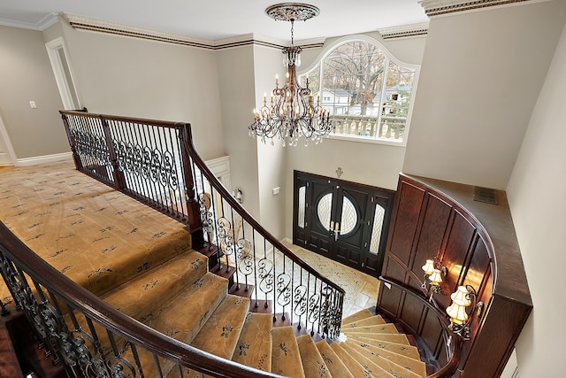 foyer with crown molding and a chandelier