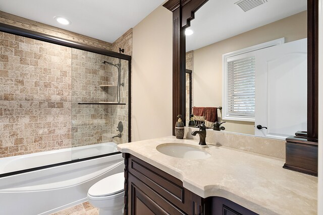 full bathroom with toilet, vanity, and bath / shower combo with glass door