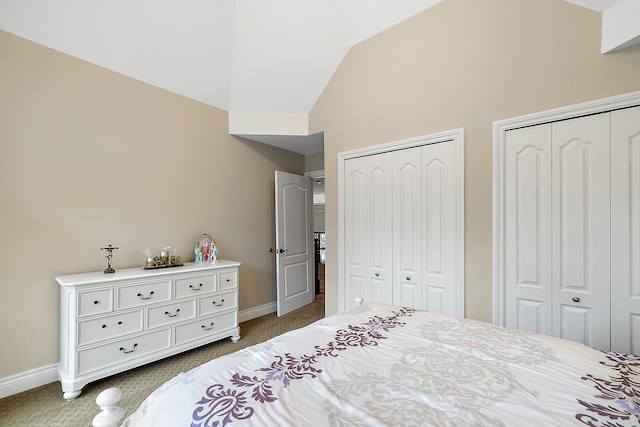 bedroom with vaulted ceiling, two closets, and baseboards