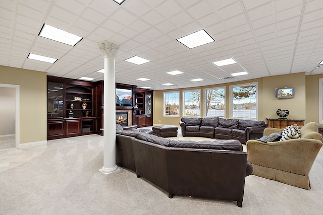 carpeted living room featuring decorative columns, a drop ceiling, and built in features