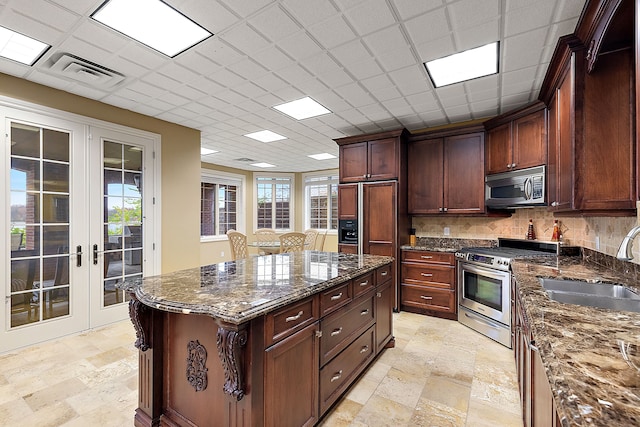 kitchen featuring stainless steel appliances, a center island, dark stone countertops, and french doors