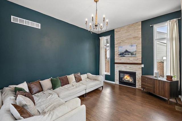 living room with an inviting chandelier, a fireplace, and dark hardwood / wood-style flooring