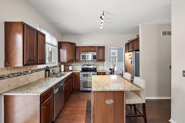 kitchen featuring dark wood-type flooring, sink, a kitchen breakfast bar, a kitchen island, and stainless steel appliances