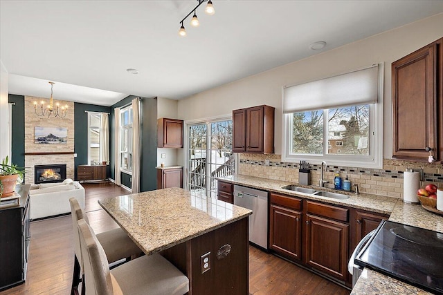 kitchen featuring a kitchen bar, sink, decorative light fixtures, a large fireplace, and stainless steel appliances