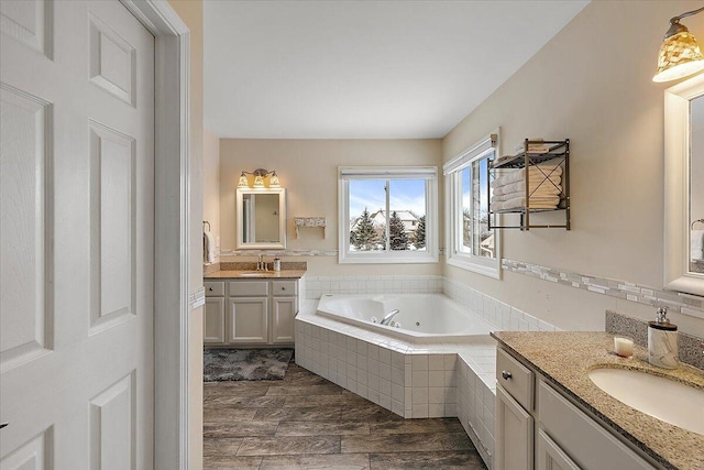 bathroom with vanity, tiled tub, and wood-type flooring