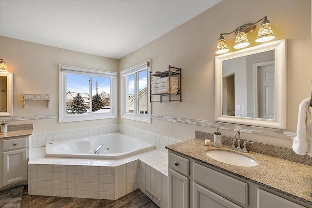 bathroom featuring hardwood / wood-style flooring, vanity, and a relaxing tiled tub