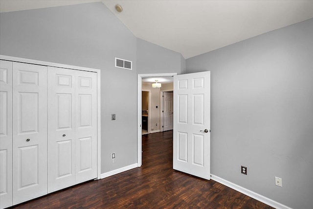 unfurnished bedroom with dark hardwood / wood-style floors, high vaulted ceiling, and a closet