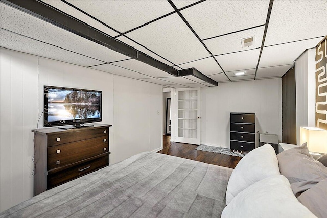 bedroom with dark wood-type flooring and a drop ceiling