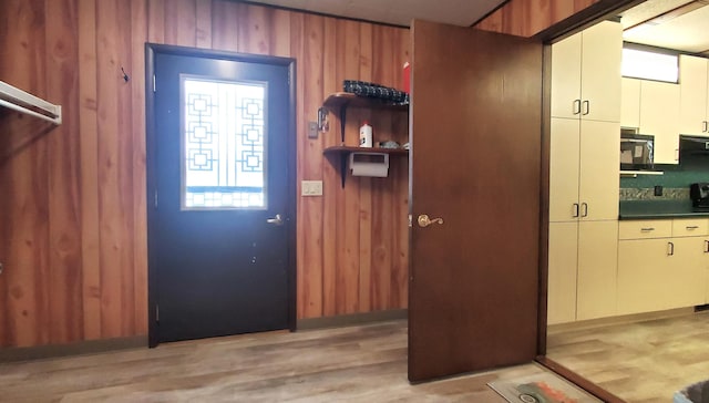 doorway to outside featuring wooden walls and light hardwood / wood-style flooring