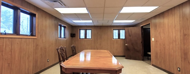 carpeted home office featuring a paneled ceiling and wood walls