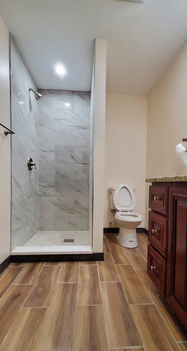 bathroom featuring vanity, a tile shower, and toilet