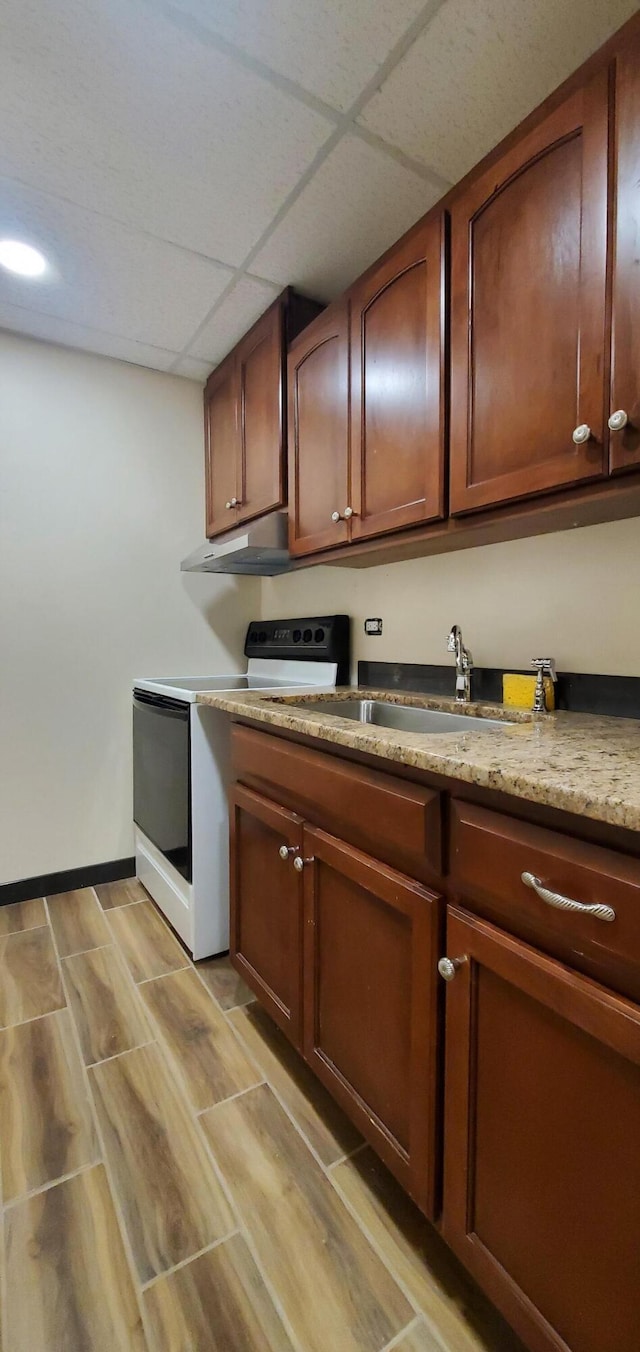 kitchen with a drop ceiling, sink, light stone counters, and white electric stove