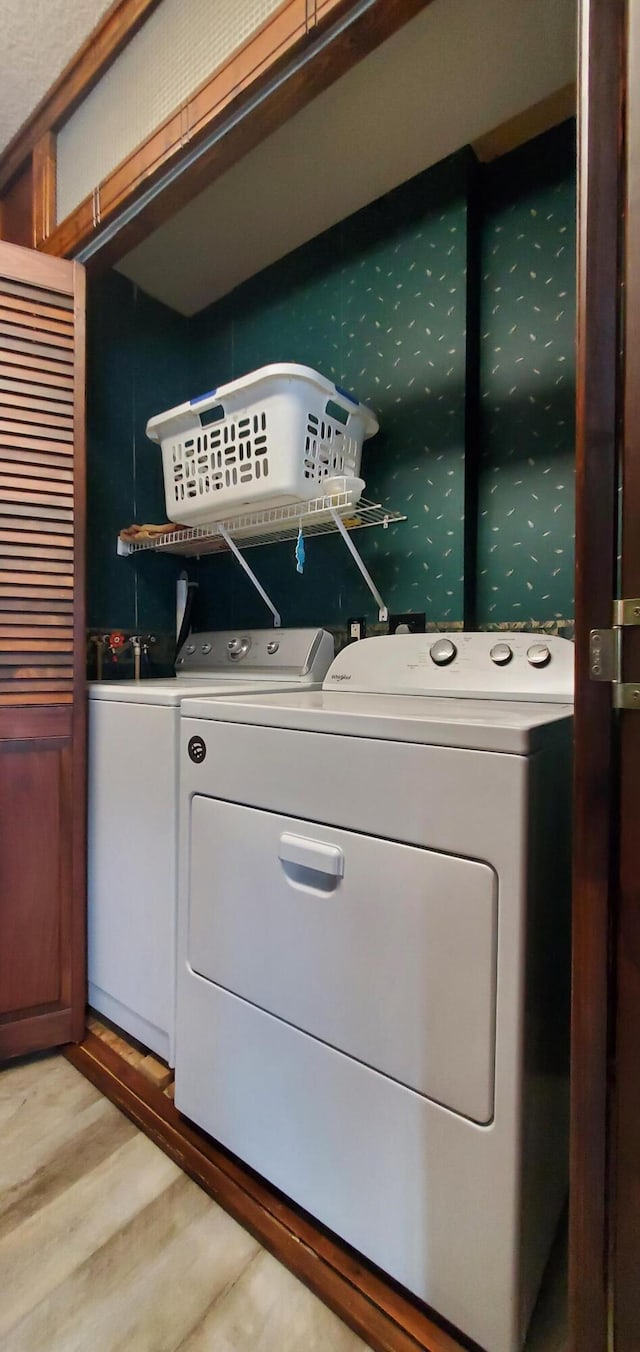 laundry area with independent washer and dryer and light hardwood / wood-style floors