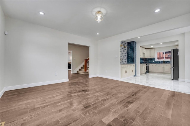 unfurnished living room featuring sink and light wood-type flooring