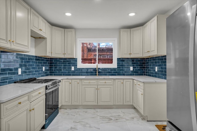 kitchen with sink, stainless steel fridge, electric range oven, light stone counters, and tasteful backsplash