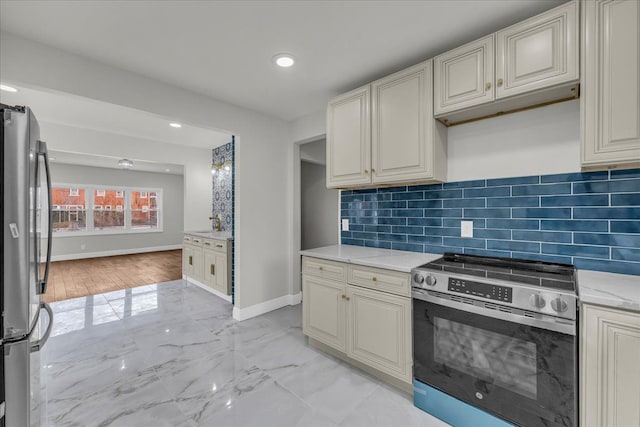 kitchen with light stone counters, tasteful backsplash, cream cabinetry, and appliances with stainless steel finishes