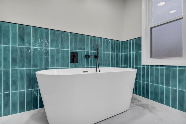 bathroom featuring a tub to relax in and tile walls