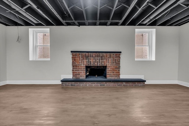 unfurnished living room featuring plenty of natural light, a fireplace, and wood-type flooring