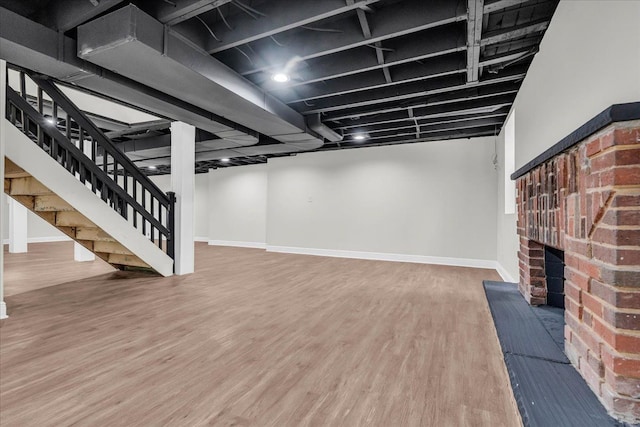 basement with hardwood / wood-style floors and a brick fireplace