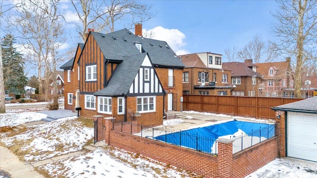 snow covered back of property featuring a garage