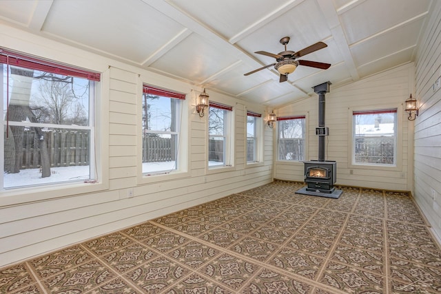 unfurnished sunroom with ceiling fan, lofted ceiling, and a wood stove