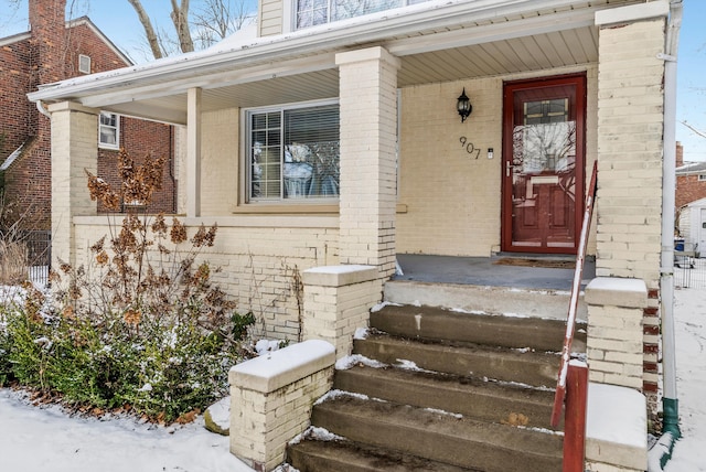 snow covered property entrance featuring a porch