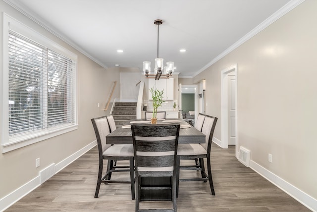 dining area featuring a notable chandelier, wood-type flooring, and ornamental molding