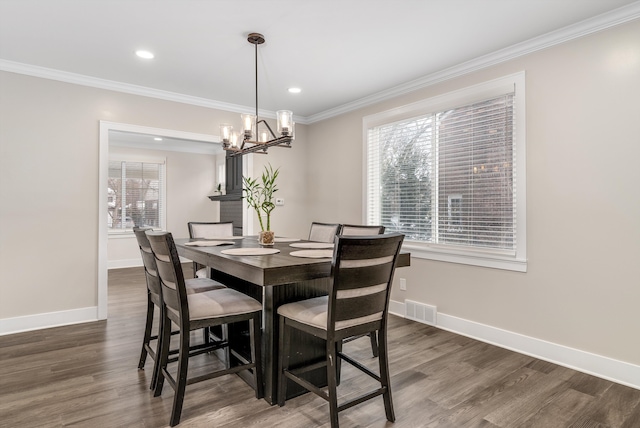 dining space with an inviting chandelier, dark wood-type flooring, and ornamental molding