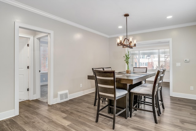 dining area featuring crown molding, dark hardwood / wood-style floors, and a chandelier