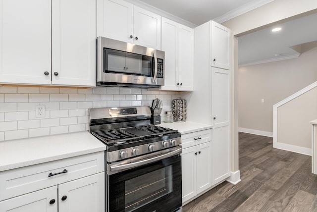 kitchen with appliances with stainless steel finishes, dark hardwood / wood-style floors, white cabinetry, decorative backsplash, and ornamental molding