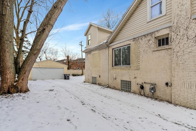 view of snowy exterior featuring a garage and an outbuilding