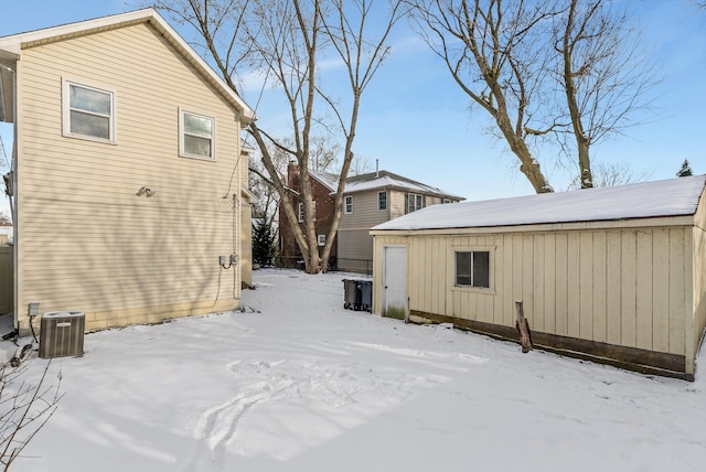 snow covered rear of property with cooling unit and an outdoor structure