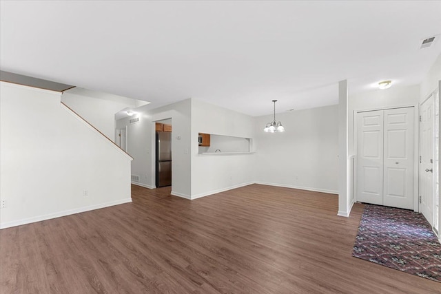 unfurnished living room featuring an inviting chandelier and dark hardwood / wood-style floors