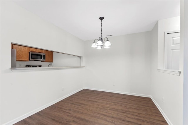 unfurnished dining area featuring dark hardwood / wood-style flooring and an inviting chandelier