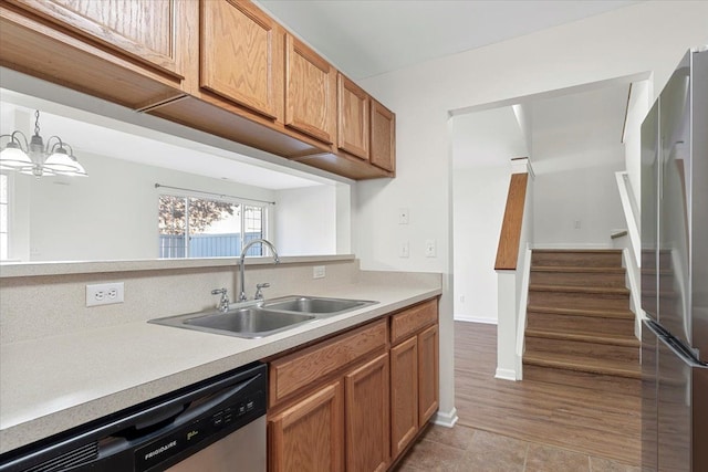 kitchen featuring appliances with stainless steel finishes, sink, pendant lighting, and a notable chandelier