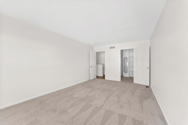 unfurnished bedroom featuring a spacious closet and light colored carpet