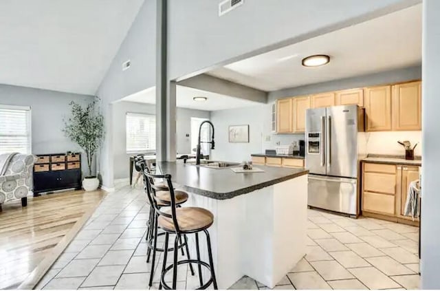 kitchen with sink, a kitchen island with sink, a wealth of natural light, stainless steel fridge with ice dispenser, and light brown cabinets