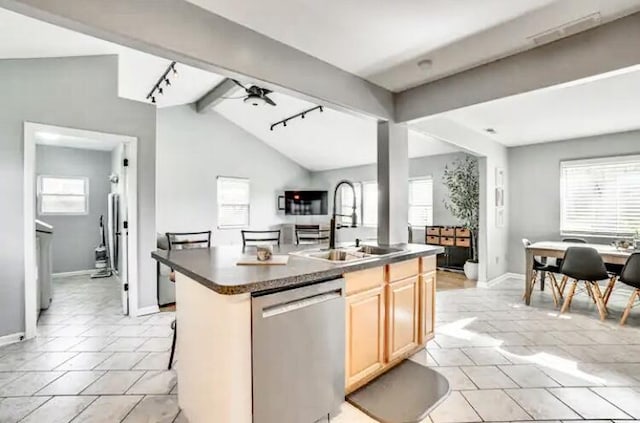 kitchen featuring dishwasher, sink, vaulted ceiling with beams, ceiling fan, and a center island with sink