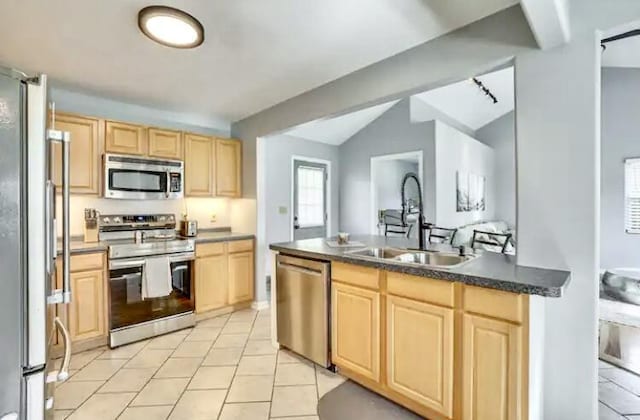 kitchen featuring lofted ceiling, sink, light tile patterned floors, light brown cabinets, and appliances with stainless steel finishes